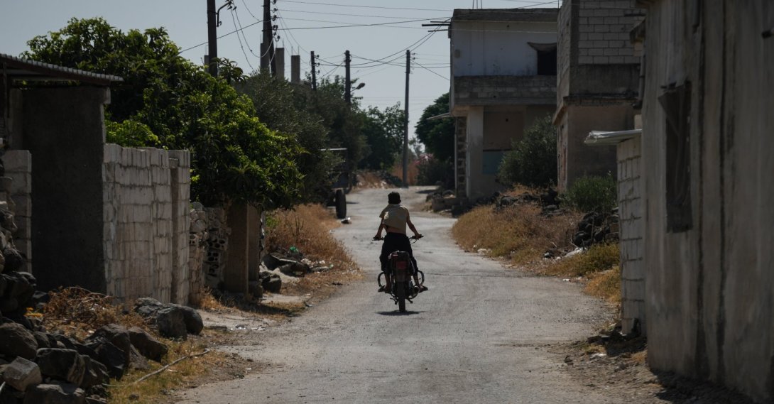This file photo shows a lone resident rides a motorcycle down an empty street in the frontline village of Abidin, west of Daraa, Syria, June 29, 2026. (Getty Images Photo)