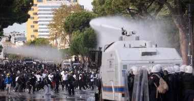 Police in riot gear stand behind an armoured police vehicle as its water cannon sprays water towards demonstrators during an anti-government protest by students, Tirana, Albania, Oct. 24, 2026. (Reuters Photo)