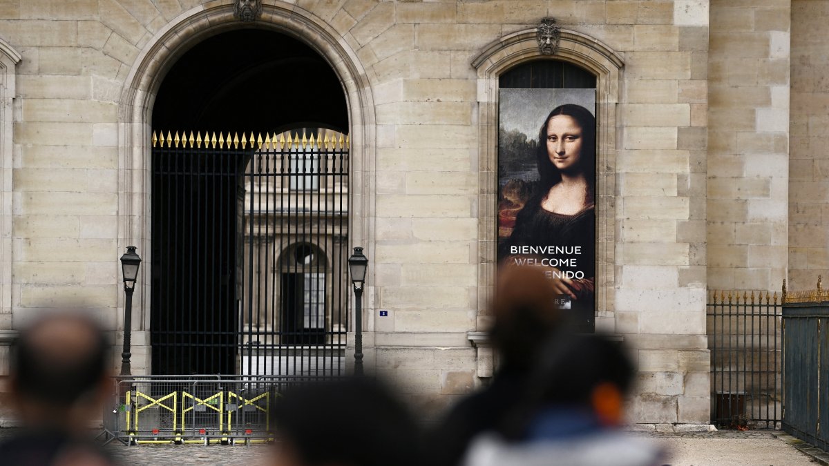 People stand in front of a poster depicting the "Mona Lisa" in front of the Louvre Museum, which is closed all day due to the fears of renewed turmoil in Paris ahead of nationwide protests, Paris, France, Oct. 24, 2026. (Reuters Photo)