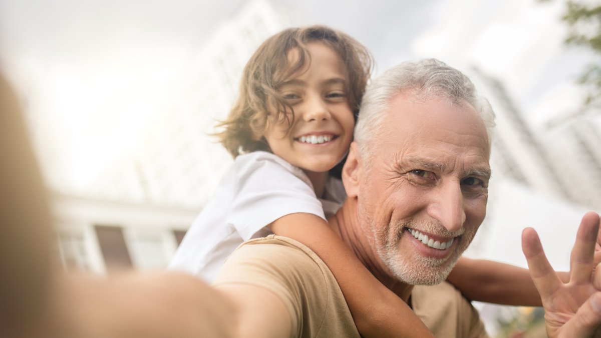 A father and his son are smiling and taking a selfie. (Shutterstock Photo)
