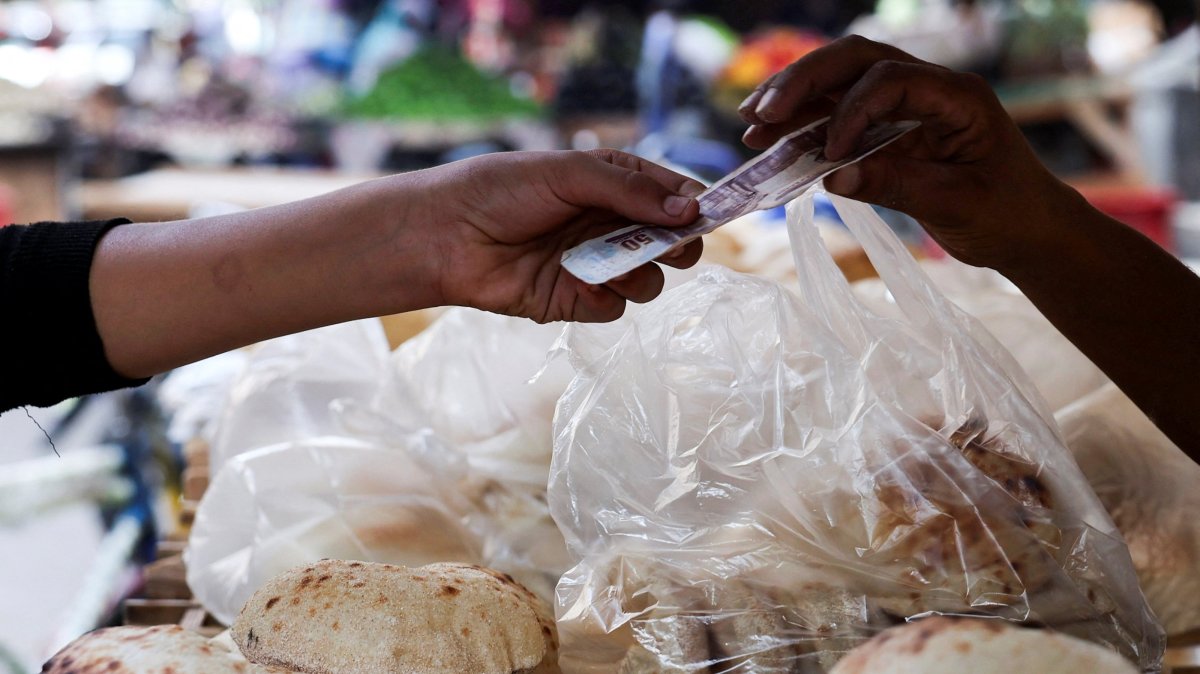 An Egyptian man buys traditional loaves of bread from a bakery, as disruptions to Black Sea grain exports and Red Sea shipping routes increase costs for wheat importers in downtown Cairo, Egypt, Oct. 13, 2026. (Reuters Photo)