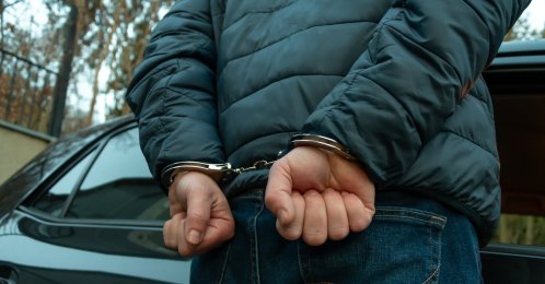 A handcuffed man is seen during an operation. (Shutterstock Photo)