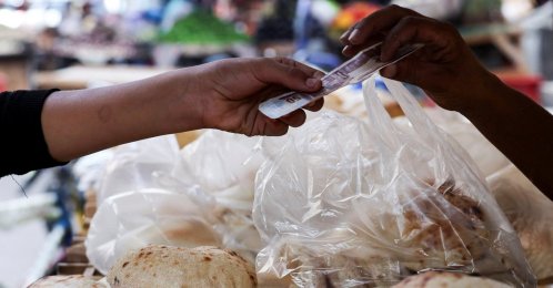 An Egyptian man buys traditional loaves of bread from a bakery, as disruptions to Black Sea grain exports and Red Sea shipping routes increase costs for wheat importers in downtown Cairo, Egypt, Oct. 13, 2026. (Reuters Photo)