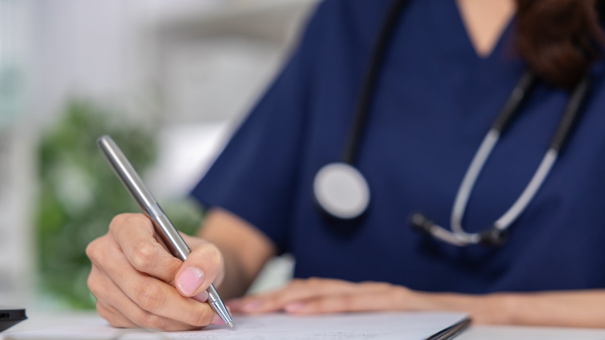 A doctor reviews medical consent forms and documents patient approvals in a clinic. (Shutterstock Photo)