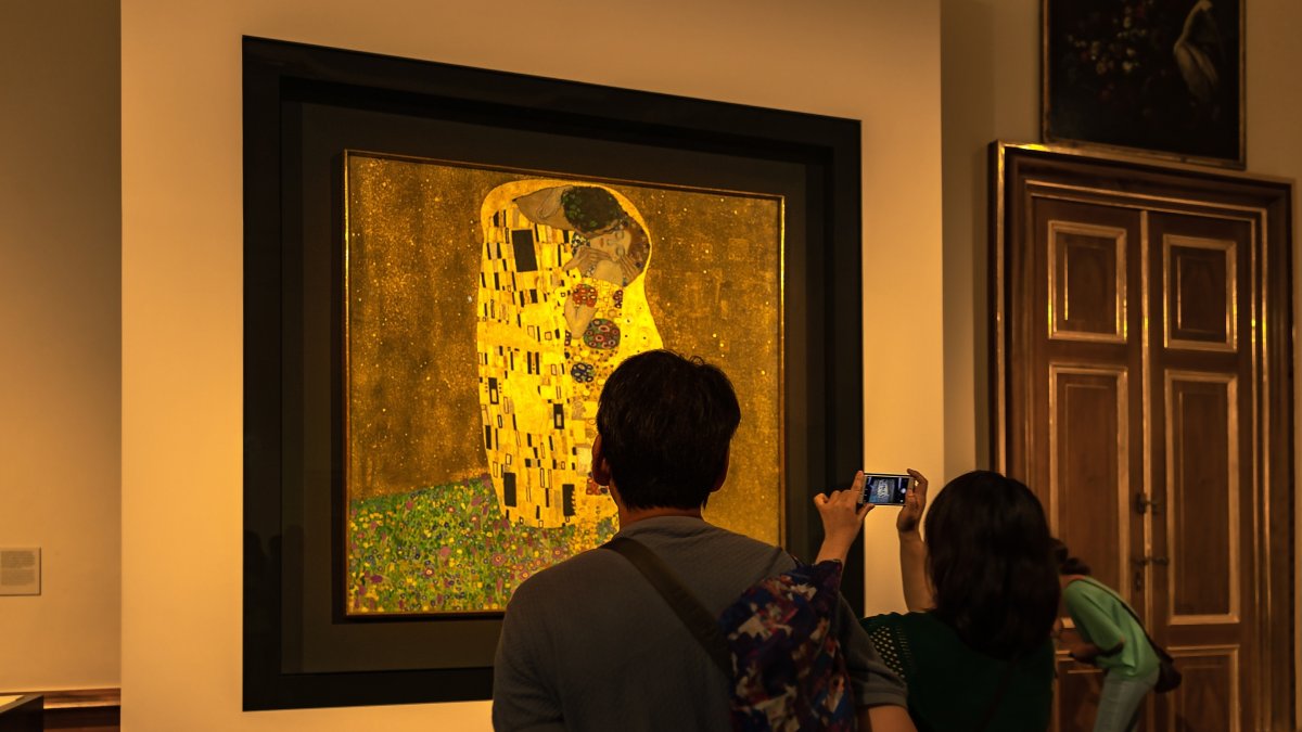 Tourists looking and taking photos near the original Gustav Klimt painting "The Kiss," Austrian Gallery Belvedere, Vienna, Austria, Aug. 25, 2022. (Shutterstock Photo)