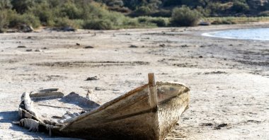An abandoned wooden fishing boat rests on the cracked, dried-up bed of a lake. (Shutterstock Photo)