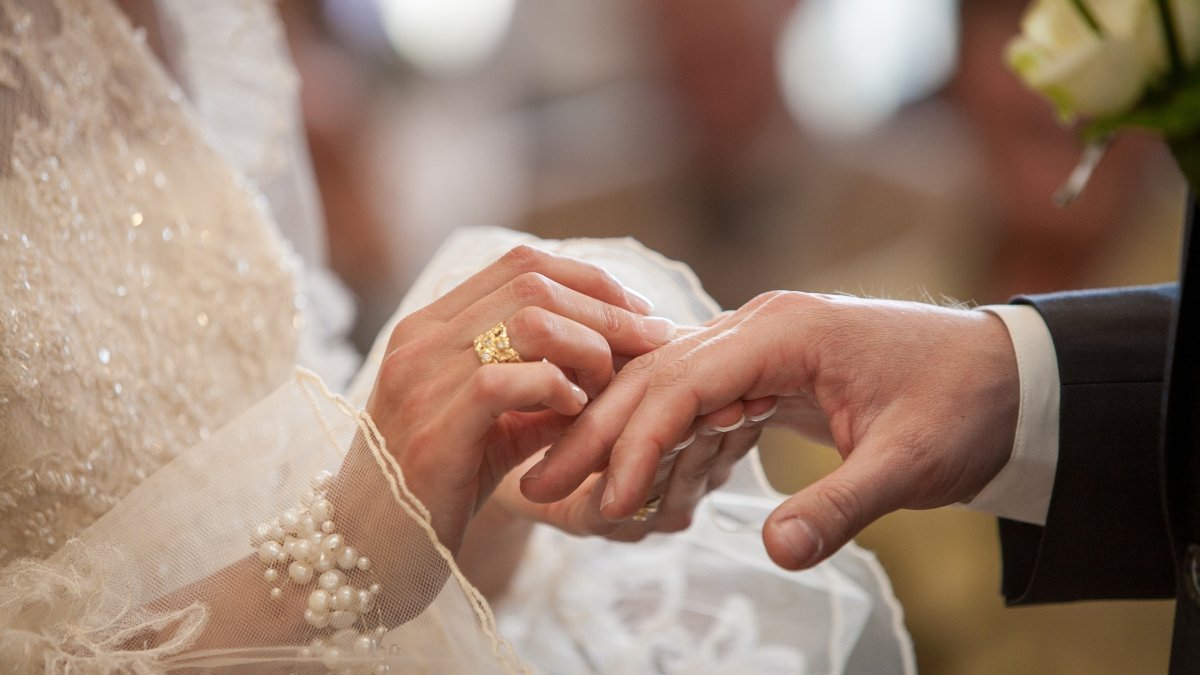 A bride and groom exchange wedding rings during their wedding ceremony. (Shutterstock Photo) 