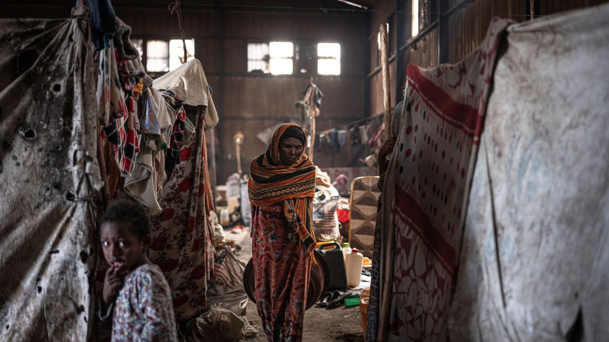 An elderly displaced Amhara woman walks inside a warehouse shared by dozens of families as insecurity in Ethiopia’s Oromia region continues to hinder their return home, at the China Camp for internally displaced people in Debre Berhan, October 19, 2026. (AFP Photo)