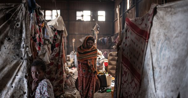 An elderly displaced Amhara woman walks inside a warehouse shared by dozens of families as insecurity in Ethiopia’s Oromia region continues to hinder their return home, at the China Camp for internally displaced people in Debre Berhan, October 19, 2026. (AFP Photo)