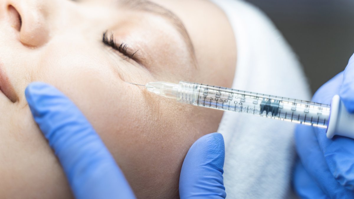 A close-up of a woman being injected with a dermal filler in the under-eye area by a cosmetician. (Shutterstock Photo)