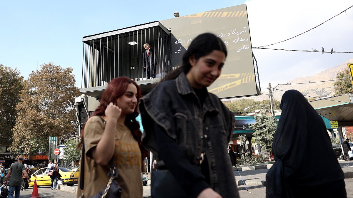 People walk past an art installation depicting a prison cell with an actor impersonating U.S. President Donald Trump behind bars, in Tajrish Square, Tehran, Iran, Oct. 26, 2026. (EPA Photo)