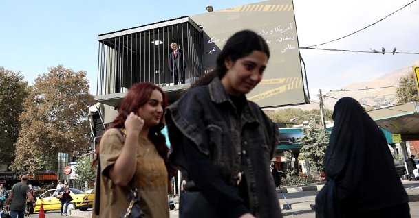 People walk past an art installation depicting a prison cell with an actor impersonating U.S. President Donald Trump behind bars, in Tajrish Square, Tehran, Iran, Oct. 26, 2026. (EPA Photo)