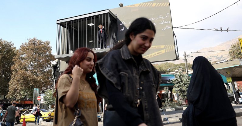 People walk past an art installation depicting a prison cell with an actor impersonating U.S. President Donald Trump behind bars, in Tajrish Square, Tehran, Iran, Oct. 26, 2026. (EPA Photo)