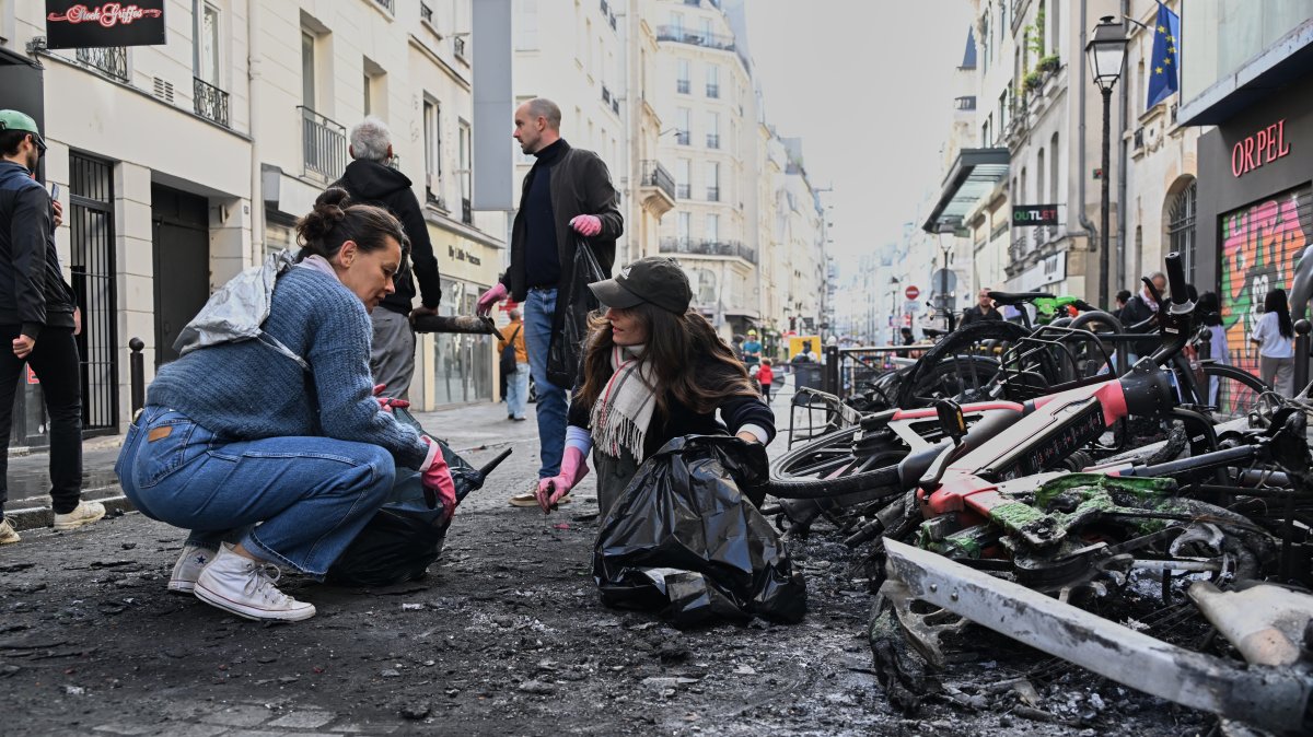 People clean up debris in a street next to burned bicycles the day after a demonstration against rising living costs and in solidarity with students' grievances, Paris, France, Oct. 18, 2026. (AP Photo)