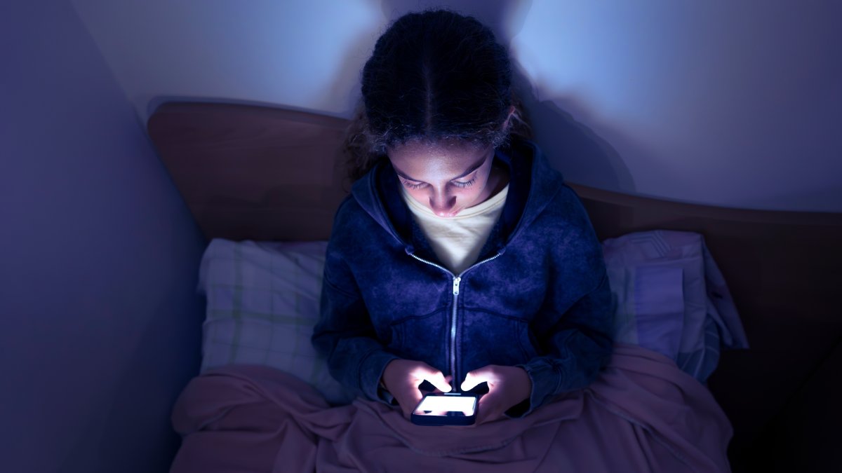 A teenager uses a smartphone in bed late at night. (Shutterstock Photo)